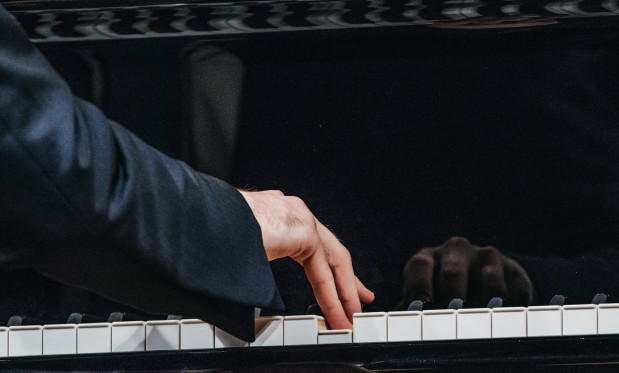 Dłoń pianisty na klawiaturze fortepianu.